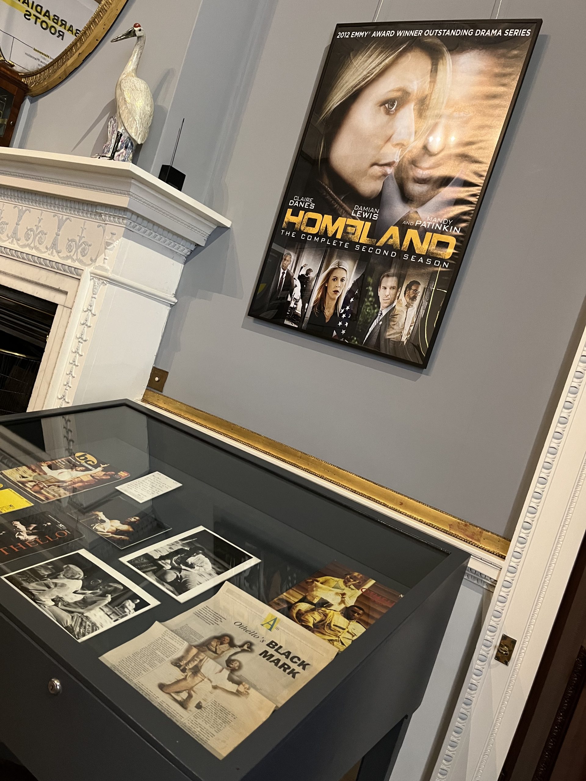 A dark blue display case containing various documents and photographs relating to David Harewood. Above is a Homeland poster.