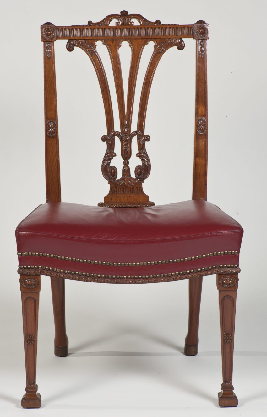 A mahogany dining chair with neo-Classical carved ornaments and a red leather upholstered seat.