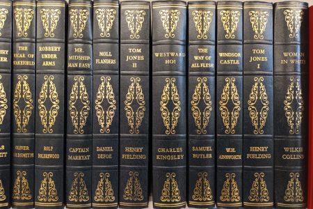 Row of 8 black leather bound vintage books with gold embossing