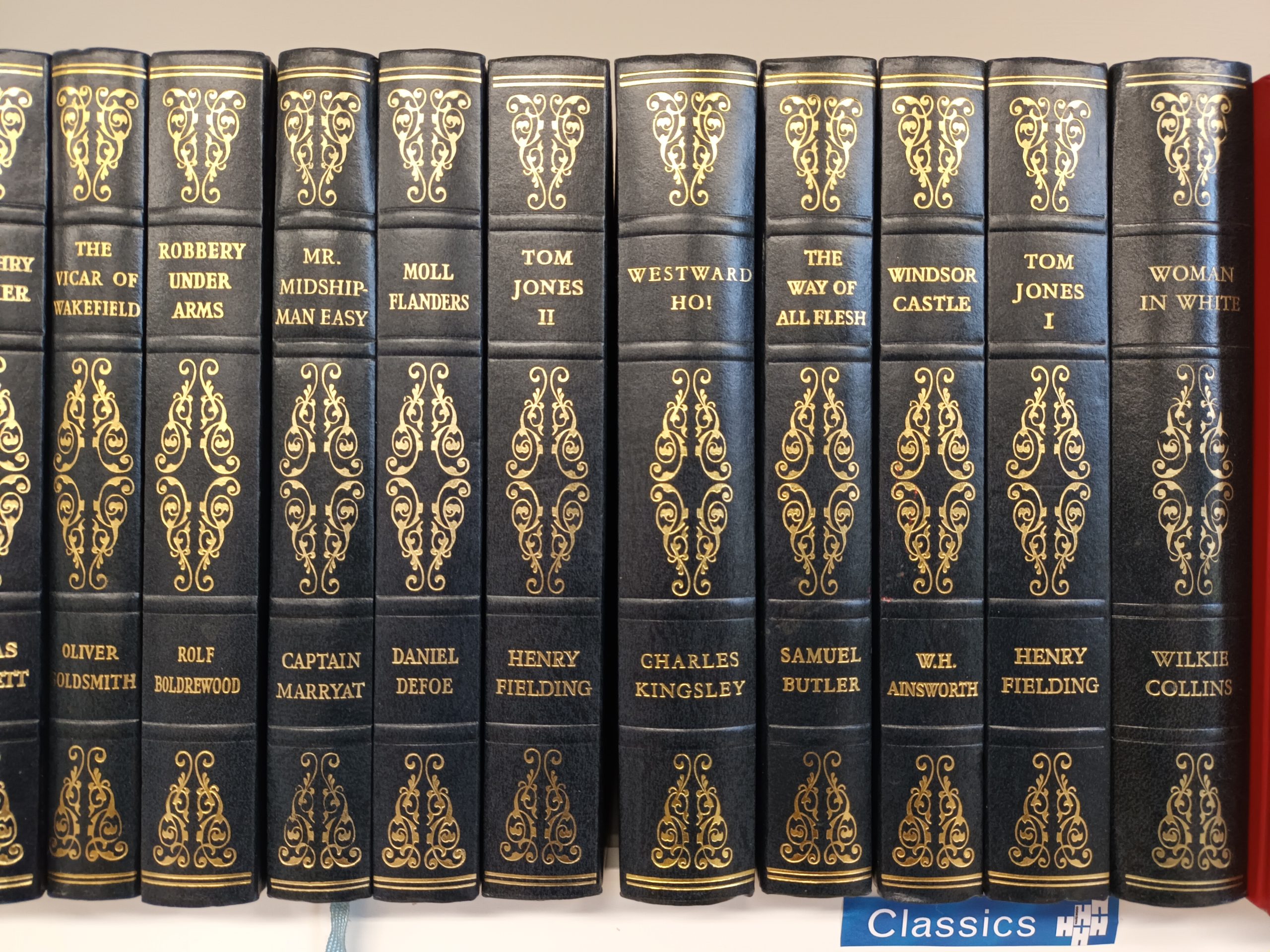 Row of 8 black leather bound vintage books with gold embossing