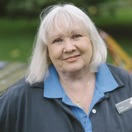 Woman with shoulder length blonde hair, in a blue polo shirt with a black jacket. On her jacket she wears her name badge on the right hand side.