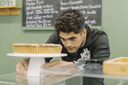 Courtyard Cafe staff member placing freshly baked French Almond Frangipane Tart on a cake stand in the Courtyard Cafe