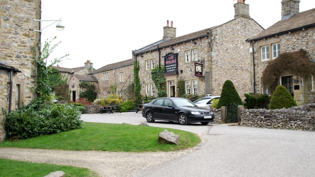 A black estate car stands on the road outside a custom built pub called the Wool Pack on the set of Emmerdale.