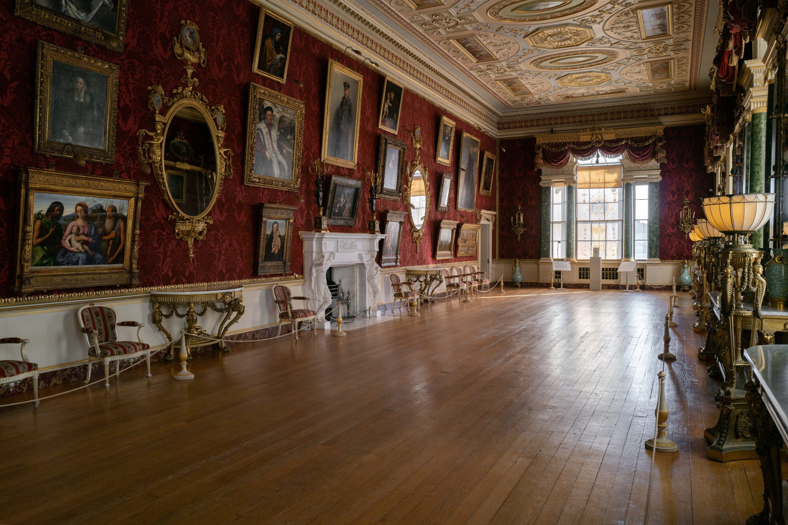 A grand long Gallery displaying an array of paintings by masters of the Italian Renaissance. Thomas Chippendale gilded mirrors cover one wall, reflecting sunlight towards the paintins. Golden lamps light up the Robert Adam ceilings which are decorated with scenes of greek mythology.