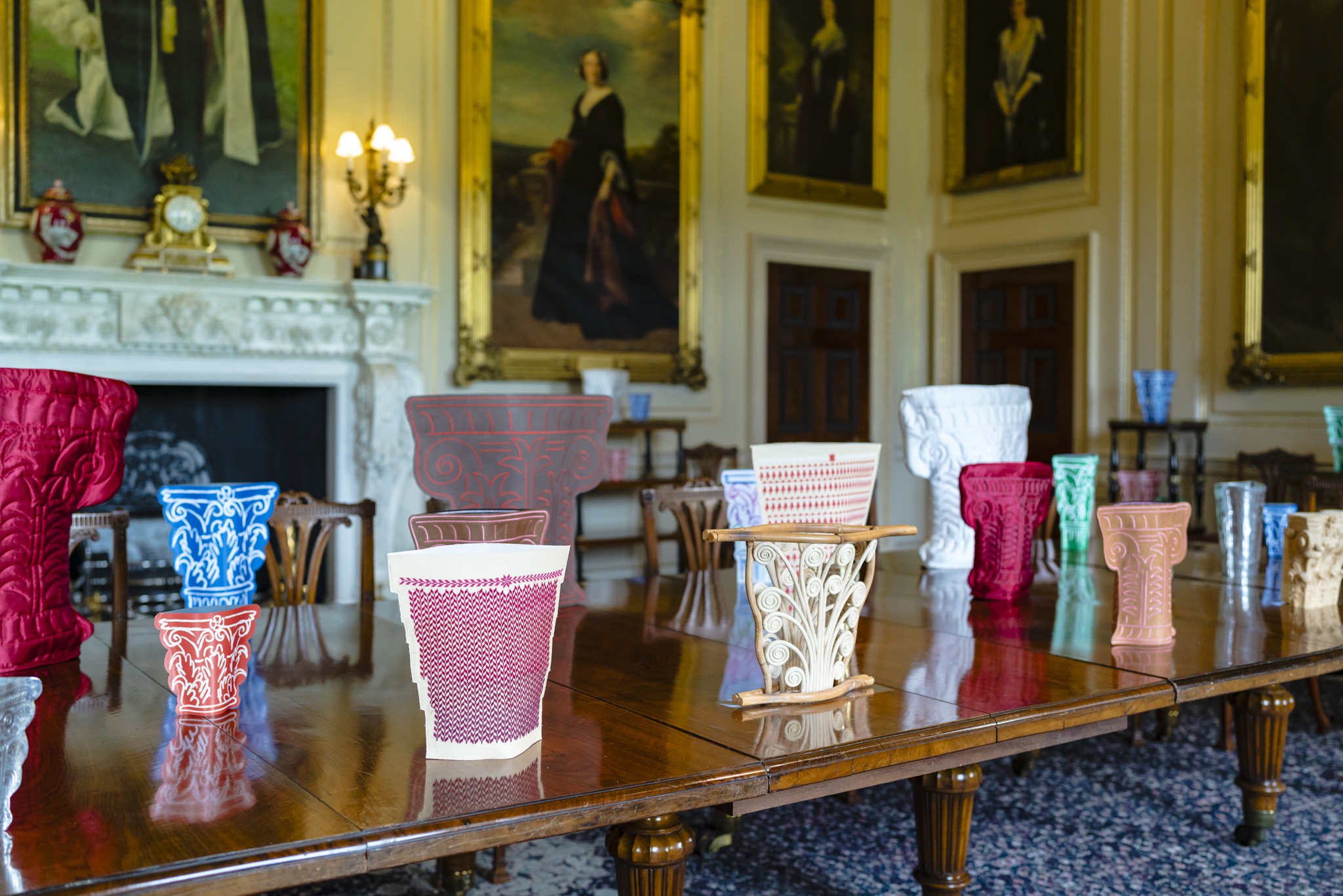 Upon an extravagant mahogany table stands a series of Corinthian-shaped vases made from leather, silk, wood and metal. Each has it's own intricate shape and colour making them highly unique. In the background hangs paintings of those who once lived at Harewood.