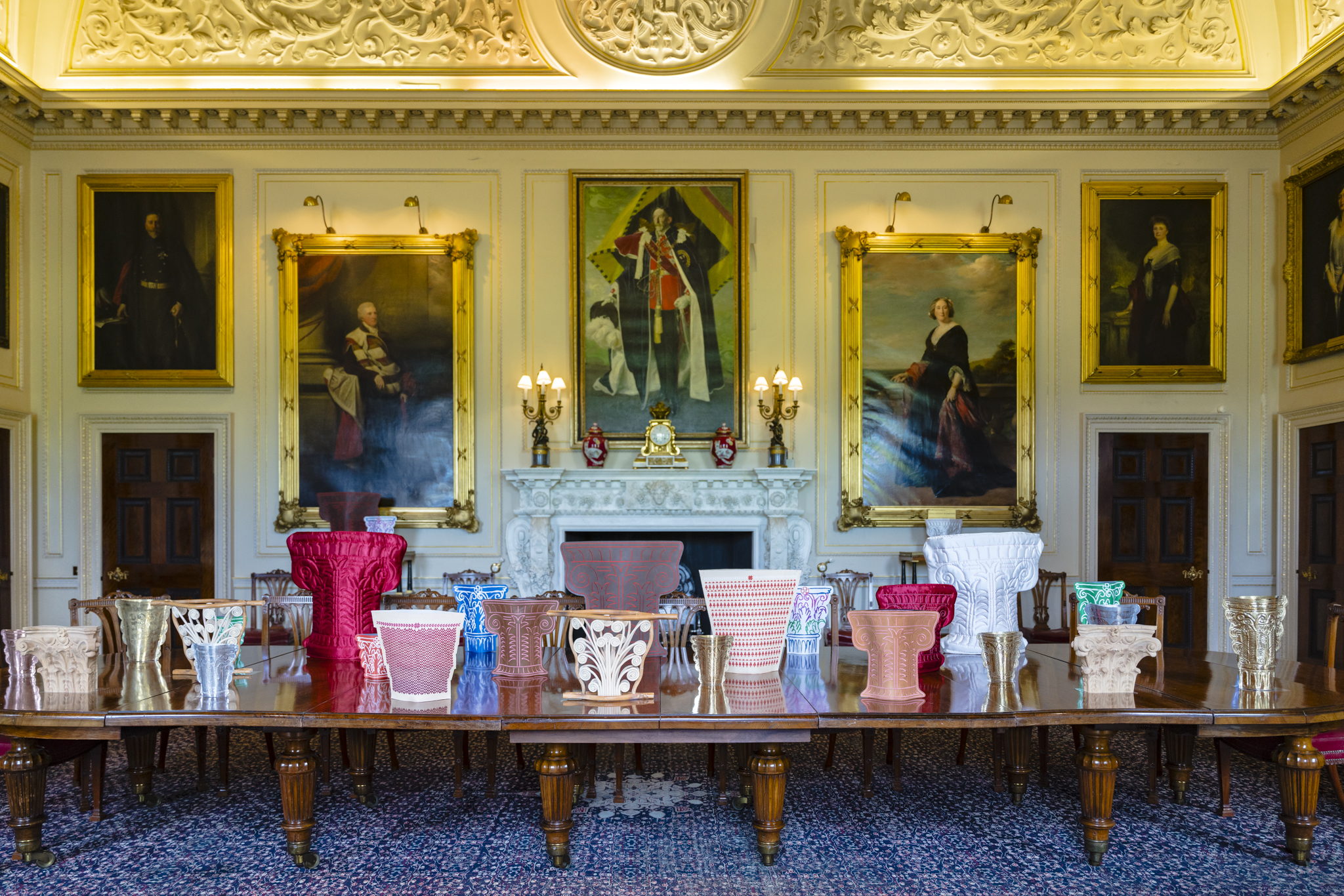 Upon an extravagant mahogany table stands a series of Corinthian-shaped vases made from leather, silk, wood and metal. Each has it's own intricate shape and colour making them highly unique. In the background hangs paintings of those who once lived at Harewood.