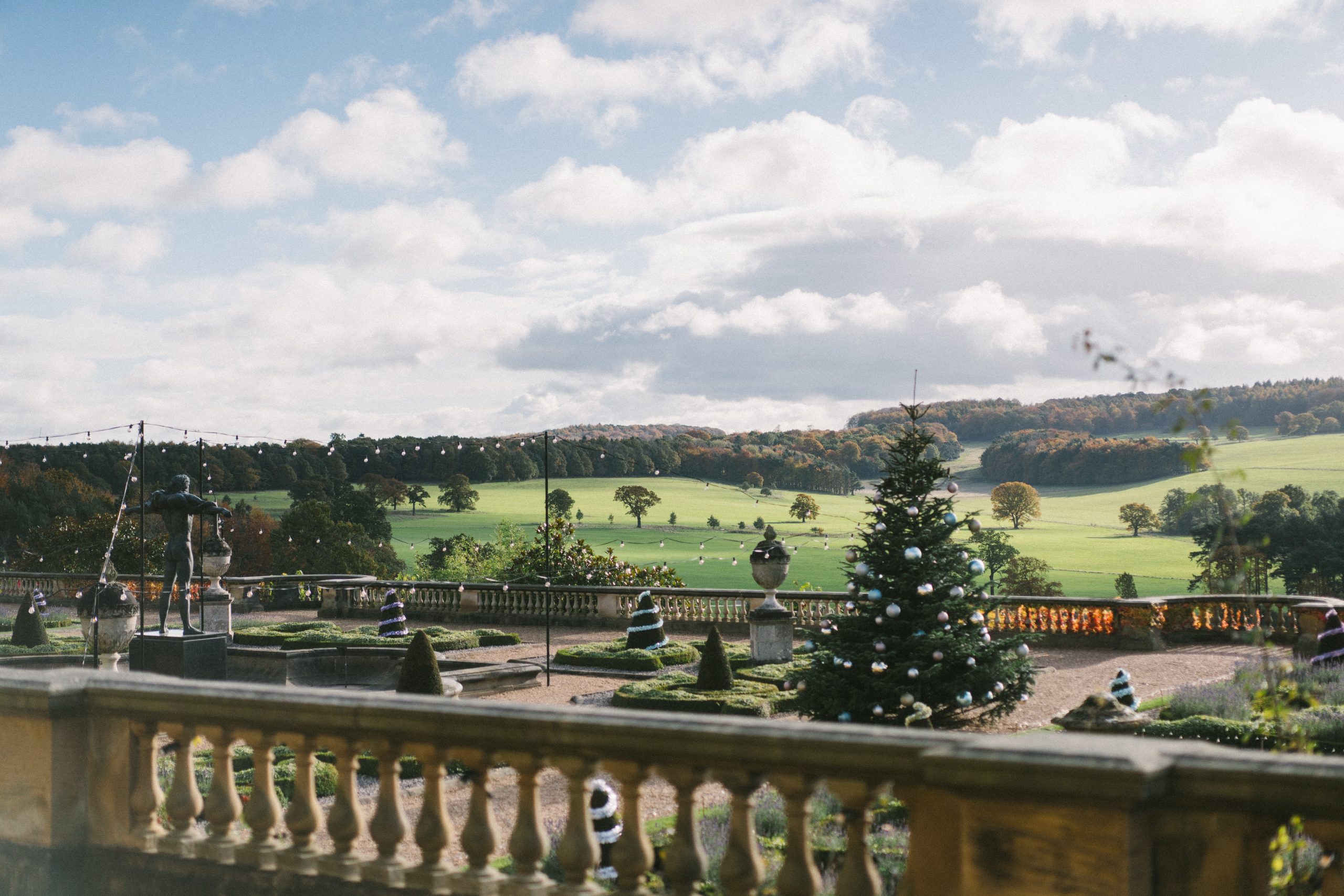 Picturesque view of rolling Capability Brown landscape from Harewood Terrace. Statue of Orpheus stands proudly to the left, with a huge Christmas Tree to the right. Festoon twinkles under the cloudy skies.