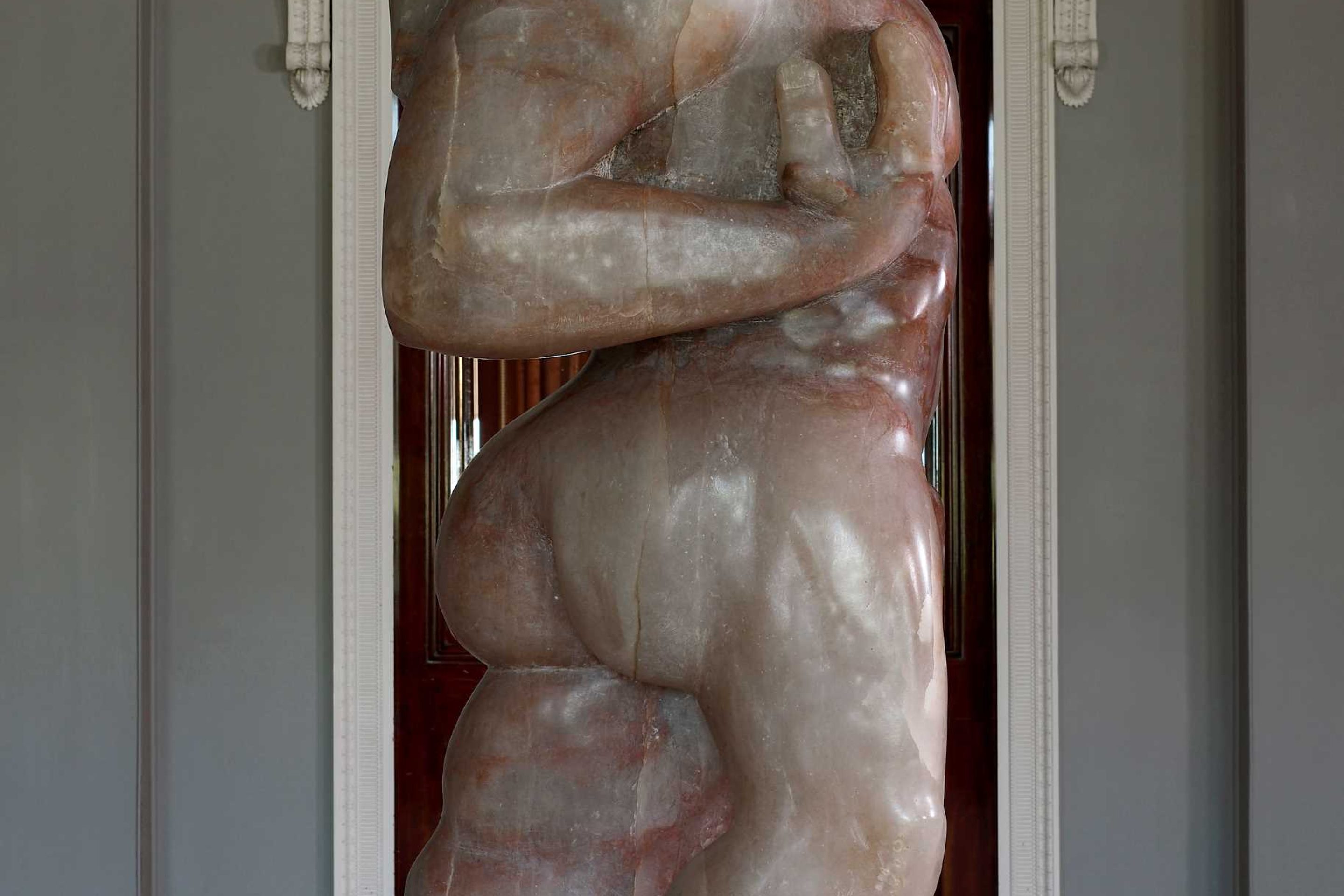 A large full-length human sculpture seen in side-profile, carved out of Derbyshire Alabaster