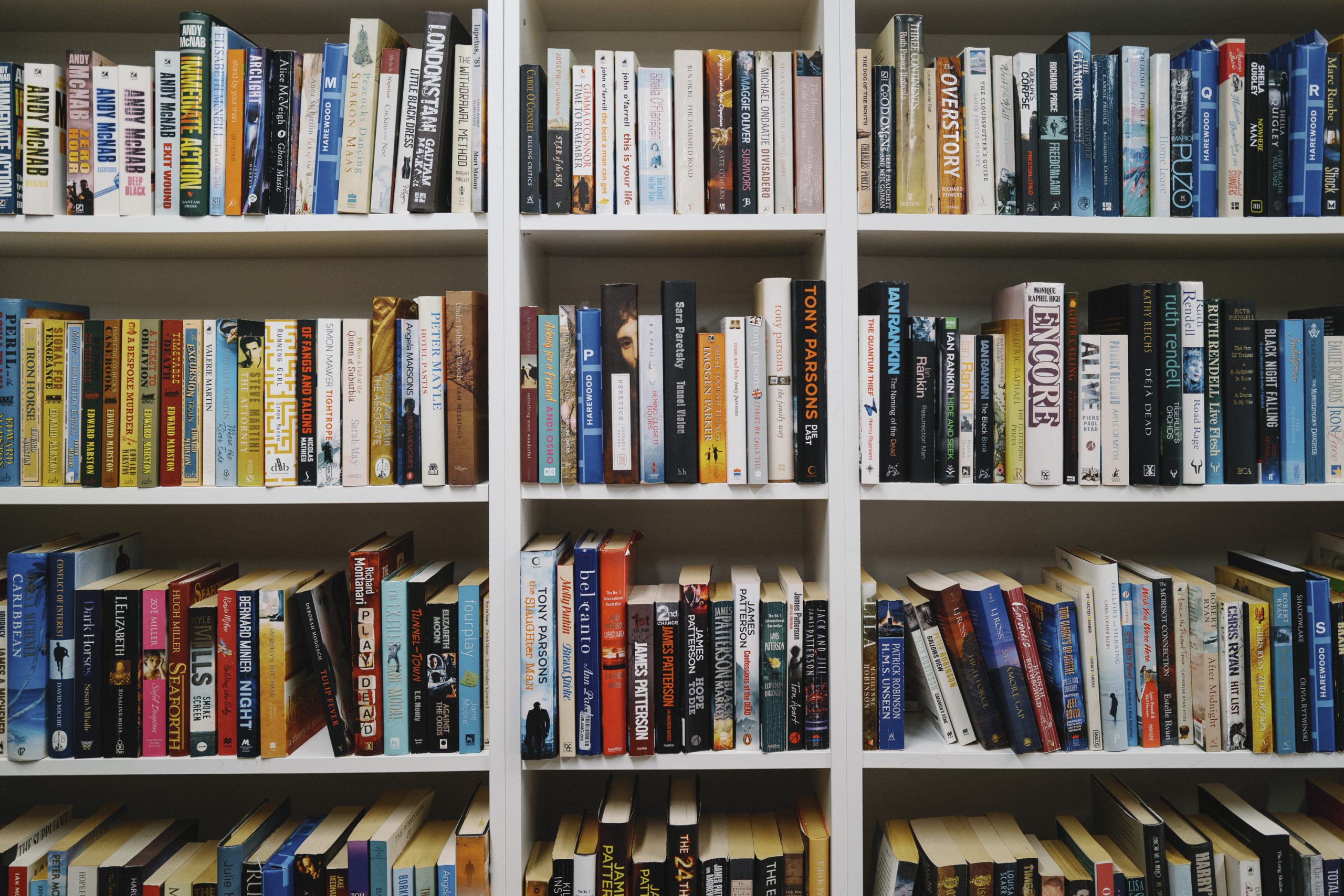 Rows and rows of book donations are neatly lined up on white shelves.