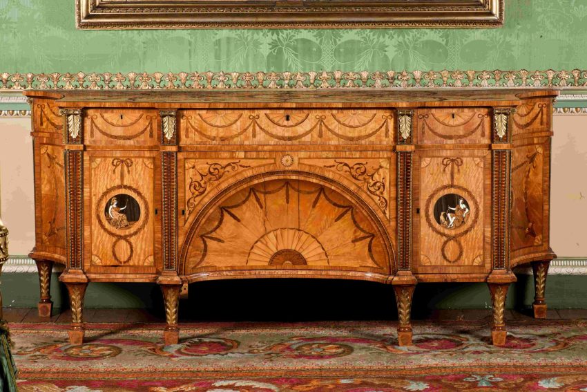 A large wooden dressing cabinet decorated with intricate marquetry patterns on a honey-coloured ground. Two marquetry roundels decorate the left and right sides, depicting the Roman godesses Diana and Minerva.