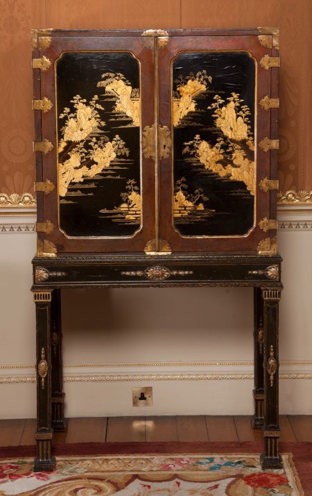 A Chinese cabinet made of black and gold lacquer mounted on a simple black painted stand made by Chippendale.