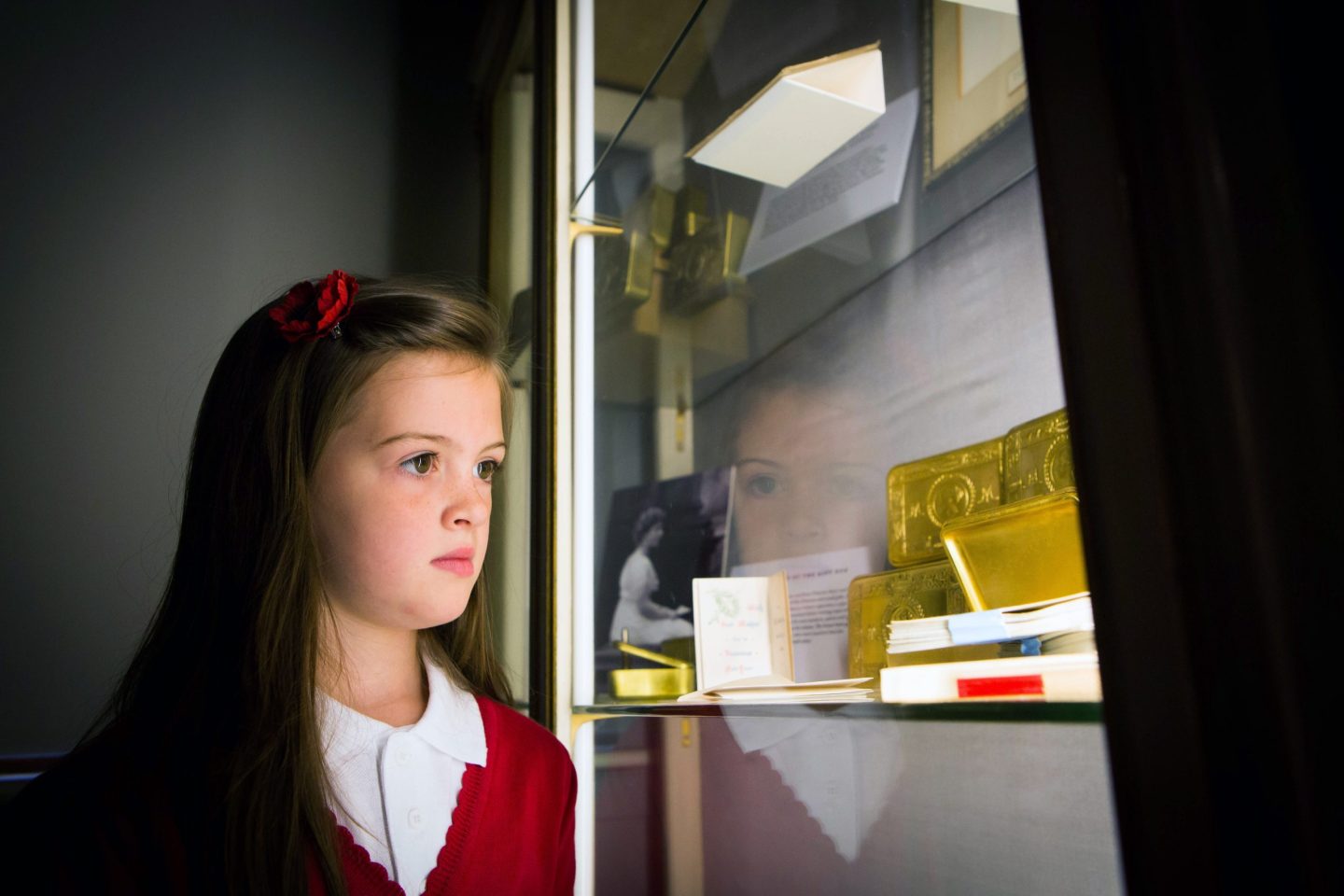 A young pupil looks into a glass cabinet at a gold box and black and white photo of a young Princess Mary.